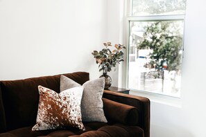 A brown sofa with two patterned cushions and a vase with a plant on a windowsill. - Newly remodeled 2br/2ba on South First! OleMiss + F1! (Austin)