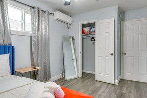 A bedroom with a bed, a bedside table, a mirror, a wardrobe, and a window with curtains. - Near Texans | NRG Stadium | Med Center | Downtown! (Houston)