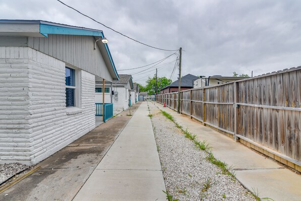 Une ruelle étroite, avec un bâtiment blanc sur la gauche et une clôture en bois sur la droite.