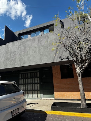 A modern building with a garage door, a tree in front, and a parked car.