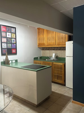 A kitchen with a central island, wooden cabinets, a refrigerator, and a tiled backsplash.