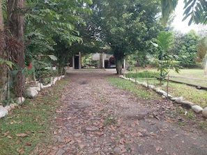 A pathway leading to a building with a covered seating area and a hammock.