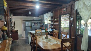 A rustic dining area with wooden furniture and a kitchen in the background. - Your Amazonian retreat, private pool, and nature (Tena)