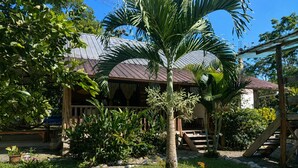 A tropical-style building with a metal roof, surrounded by lush greenery and a well-maintained garden. - Your Amazonian retreat, private pool, and nature (Tena)