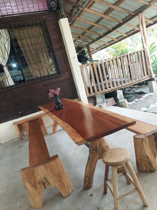 A wooden dining table with benches, a small stool, and a vase with flowers.