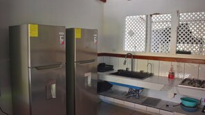 Una cucina funzionale con frigorifero in acciaio inossidabile, lavandino e un finestrino con decorazione a reticolo.