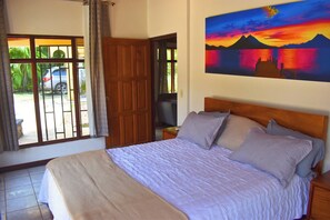 Une chambre à coucher avec un lit, un tableau, une télévision et une vue sur une voiture garée à l’extérieur.