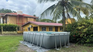 Un quartiere residenziale con piscina, una casa con tetto rosso e una palma.