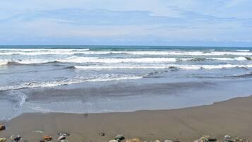 Una playa con olas, piedras y cielo despejado.