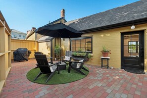A patio area with a brick floor, outdoor furniture, and a large umbrella. - Kimball Island | River Views | Walk Downtown (Exeter)