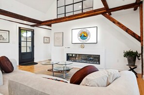 A modern living room with a fireplace, a glass coffee table, and a sofa. - Kimball Island | River Views | Walk Downtown (Exeter)