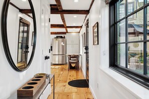 A narrow hallway with wooden flooring, a wooden bench, and a large window on the right.