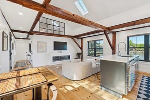 A spacious kitchen with a large island, a dining area with a bamboo table, and a living room with a sofa. - Kimball Island | River Views | Walk Downtown (Exeter)