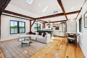 A spacious living area with a sofa, coffee table, and a view of a lake through large windows.