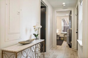 A hallway with a marble table, a vase with white flowers, and a bowl of decorative items. - Coastal Grand Koz | Steps to Beach | Ocean View (Salisbury)
