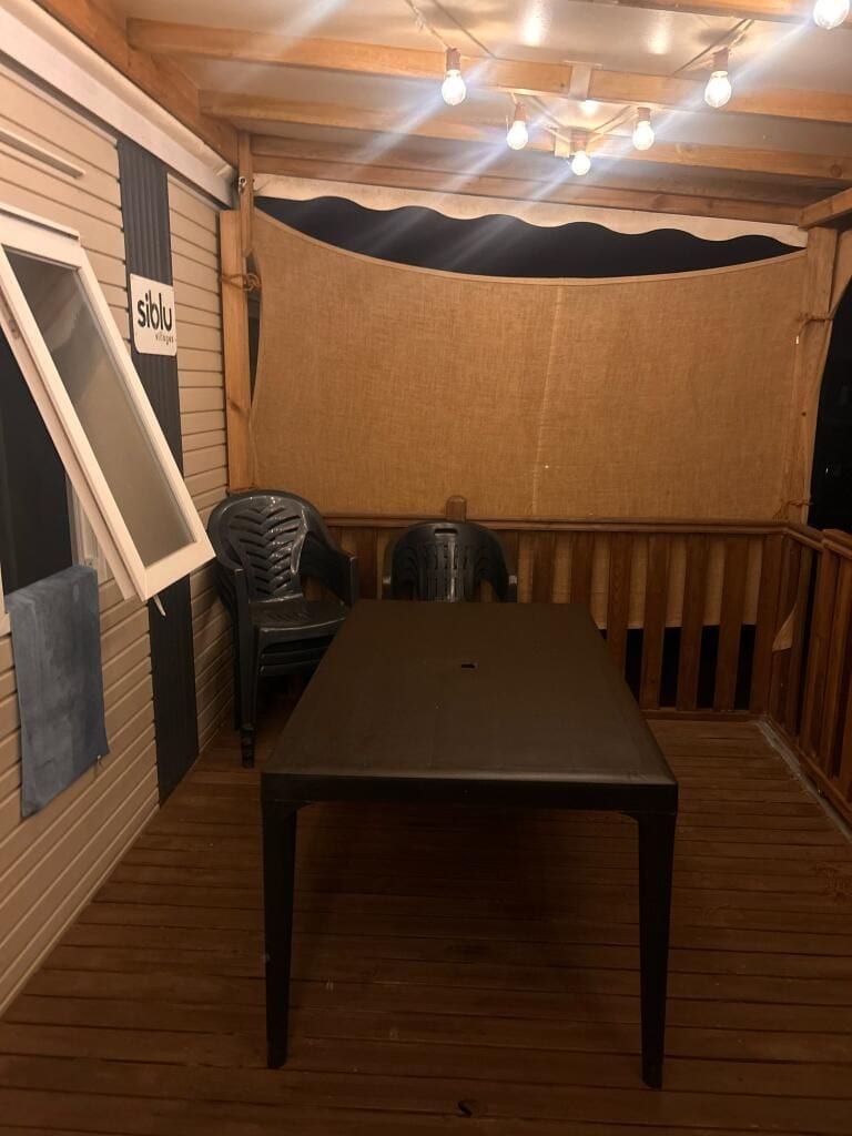 A wooden deck with a table and chairs, a covered area, and a sign that reads 'stolu village.'