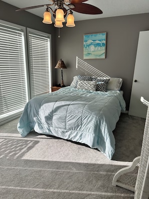 A bedroom with a bed, a ceiling fan, a lamp, and a painting on the wall. - Home on the Cove is lakefront with a private dock (Sunrise Beach)