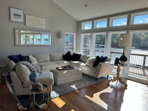 A spacious living room with a large sectional sofa, a coffee table, and a view of a body of water through large windows. - Home on the Cove is lakefront with a private dock (Sunrise Beach)