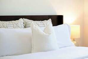 A neatly made bed with white linens and a single white pillow. - Beach Living at Plantation Village BLD (George Town)