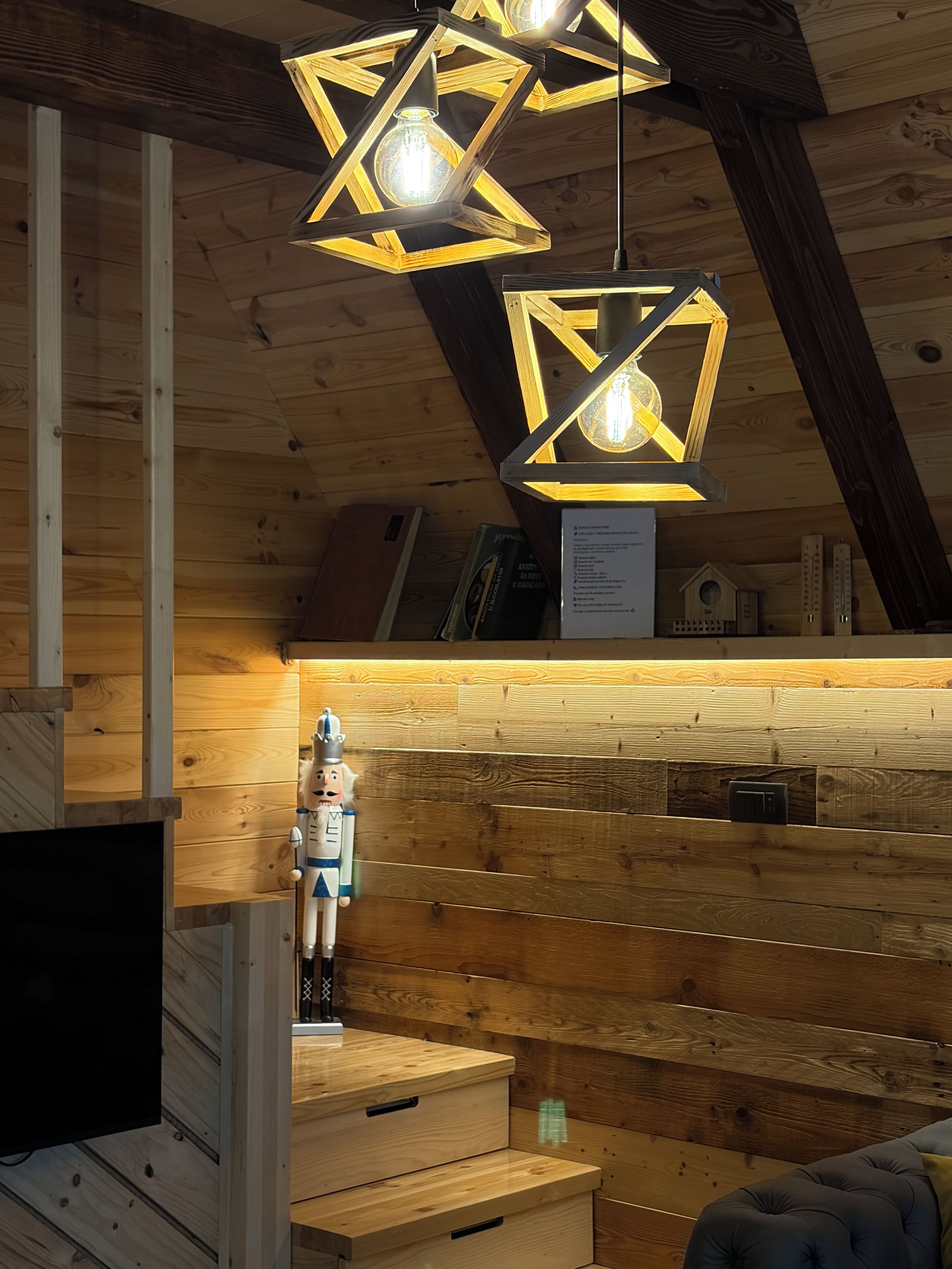 Un intérieur en bois agrémenté de luminaires suspendus en forme d’étoile, d’un meuble en bois et d’un canapé bleu moelleux.
