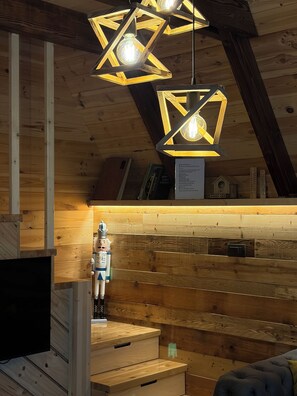 A wooden interior with star-shaped hanging lights, a wooden cabinet, and a plush blue sofa.