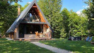 Une cabane moderne dotée d’un toit en pente, d’un balcon et d’un espace patio aménagé avec du mobilier d’extérieur.