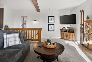 Un salon avec un canapé, une table basse, un téléviseur et une cheminée en pierre.