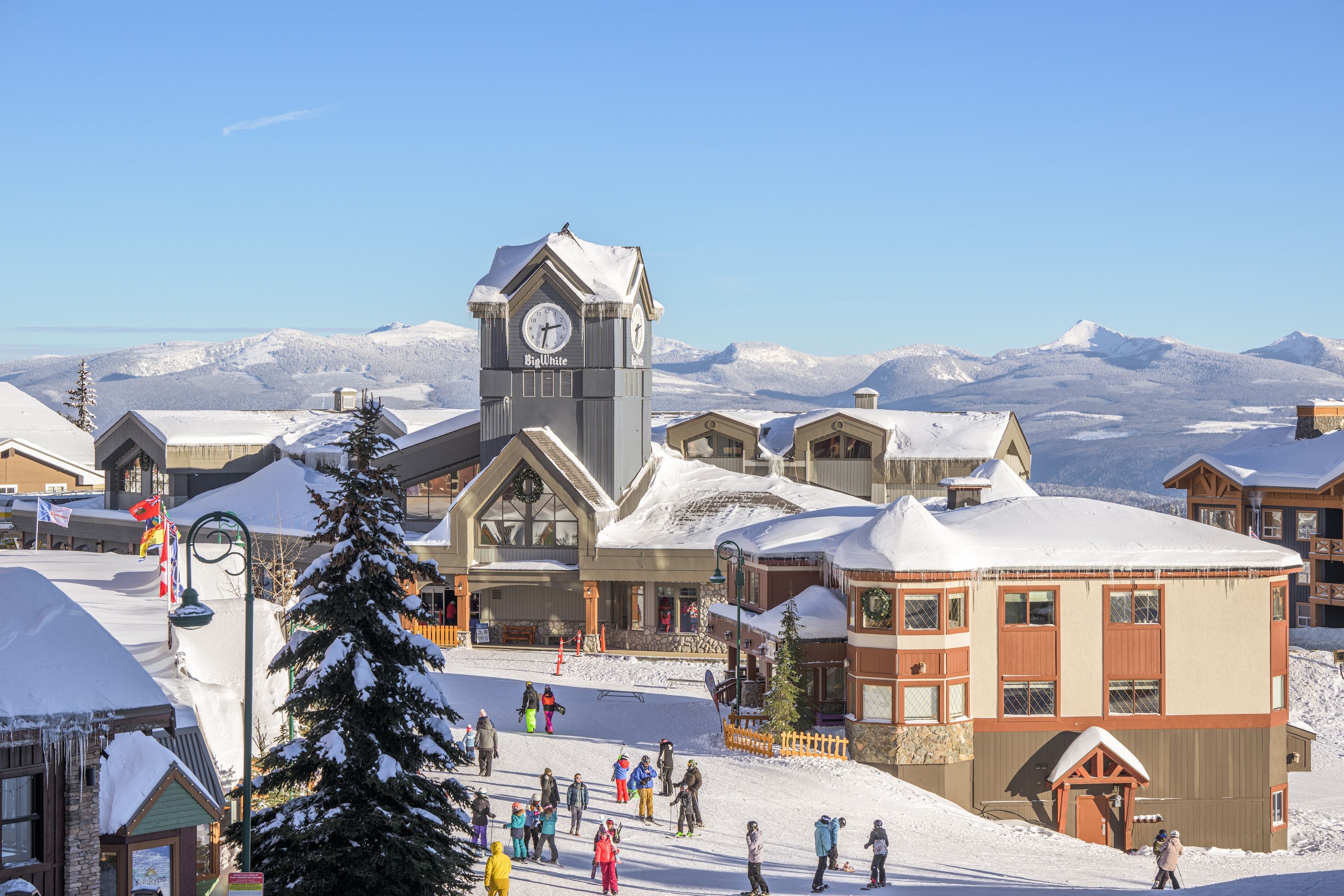 A snow-covered mountain town with a prominent clock tower, ski slopes, and a variety of buildings.