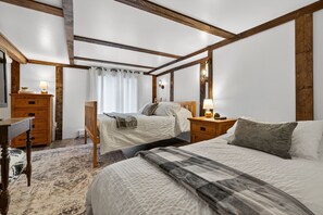 Une chambre à coucher avec un grand lit, un lit plus petit, une table de chevet, une commode et une chaise.