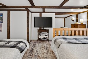 A room with two beds, a television, a small table, and a wooden headboard. - Big White Ski-In/Ski-Out Townhome | Private Hot Tub + Mountain Views (Kootenay Boundary E / West Bo*)