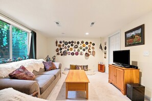 Ein gemütliches Wohnzimmer mit einer Couch, einem Couchtisch und einem Fernseher auf einem Holzschrank.