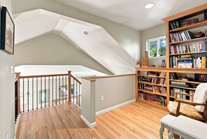 A spacious room with a wooden staircase, a bookshelf filled with books, and a window with a view of greenery. - Spacious 2400 sq ft NoBo Home: Restaurants - Hiking - Trails - Quiet (Boulder)