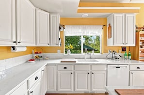 A kitchen with white cabinets, a window with a view of greenery, and a sink. - Spacious 2400 sq ft NoBo Home: Restaurants - Hiking - Trails - Quiet (Boulder)