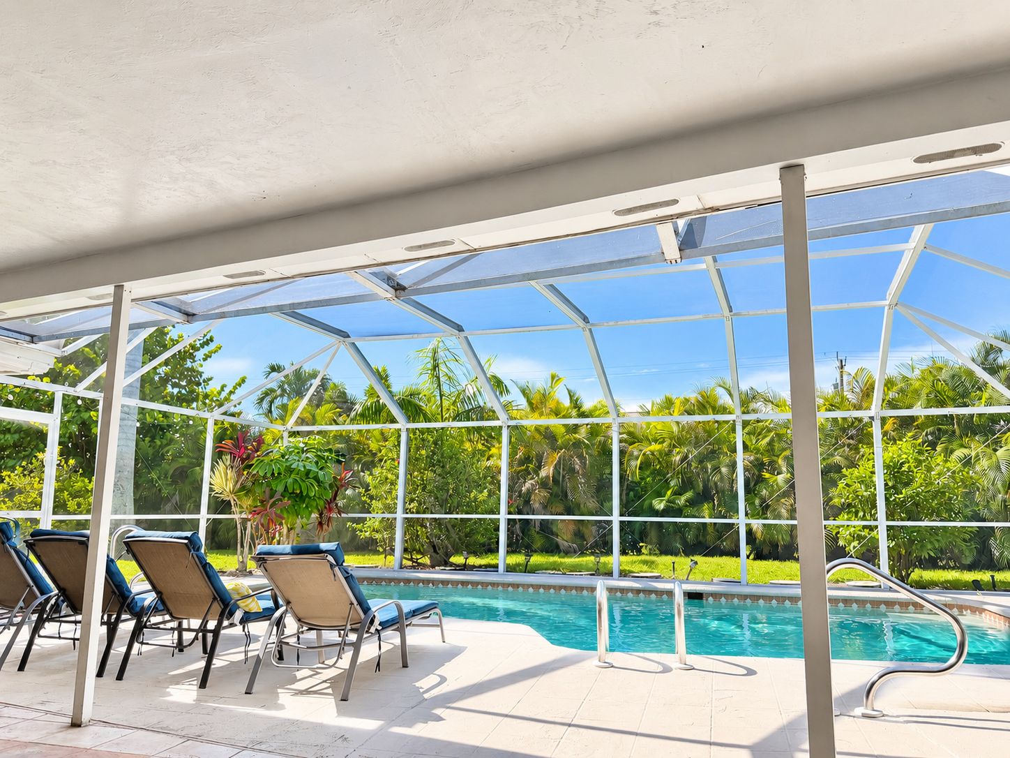 A covered pool area with lounge chairs and a view of the surrounding greenery.