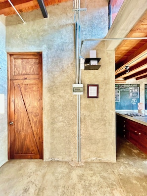 A room with a wooden door, a concrete wall, and a gas stove.