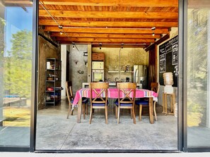 A dining area with a wooden ceiling, a table with a pink tablecloth, and chairs.