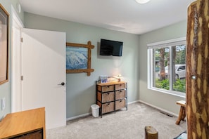 A room with a mounted television, a wall-mounted map, a small table with a lamp, and a window with a view of the outside. - 2BR Condo for 6 w Shared Hot Tub, Near Mtn & Lakes (Mammoth Lakes)
