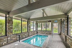 An indoor swimming pool with stone walls and a covered roof, surrounded by windows. - 2BR Condo for 6 w Shared Hot Tub, Near Mtn & Lakes (Mammoth Lakes)