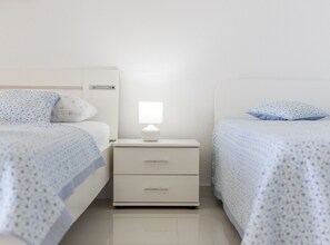 Ein Hotelzimmer mit zwei Betten, einem Nachttisch mit Lampe und einem an der Wand montierten Heizgerät.