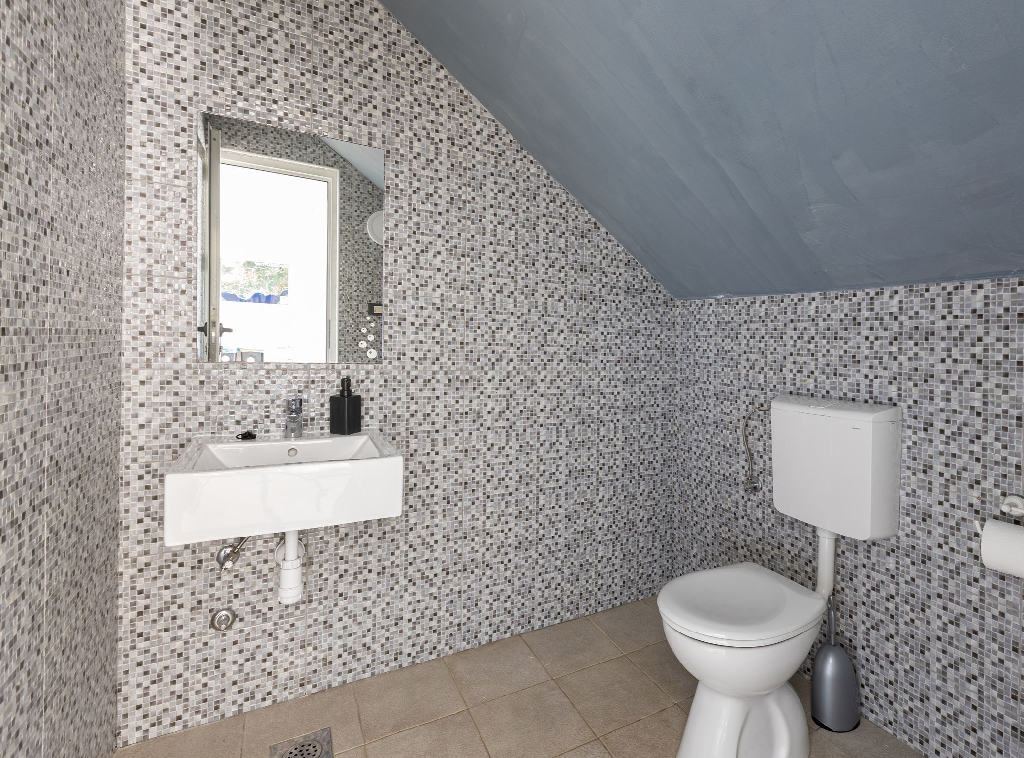 A bathroom with a white sink, a toilet, and a mirror.