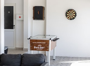 Ein Zimmer mit Dartscheibe, einer Couch und einem Tisch mit Holzbeschichtung.