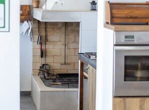 Eine Küche mit Backsteinwand, Grill und Edelstahlbackofen.