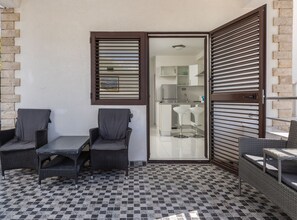 Ein Balkon mit Korbmöbeln, einem Schachbrettfußboden und Blick ins Badezimmer.