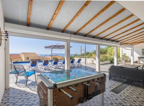 Ein Außenpoolbereich mit Liegestühlen, einem Kicker und Blick aufs Meer.