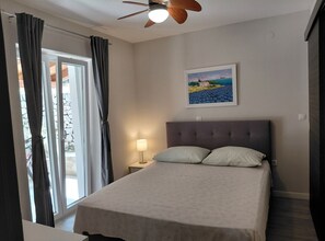 A bedroom with a bed, a nightstand, a lamp, a ceiling fan, and a painting on the wall. - One Bedroom Holiday Home with Terrace (Gruda)