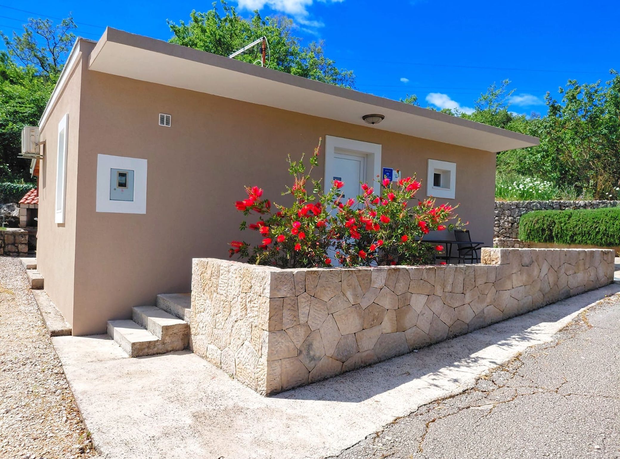 A small, single-story building with a stone foundation, a flat roof, and a door.