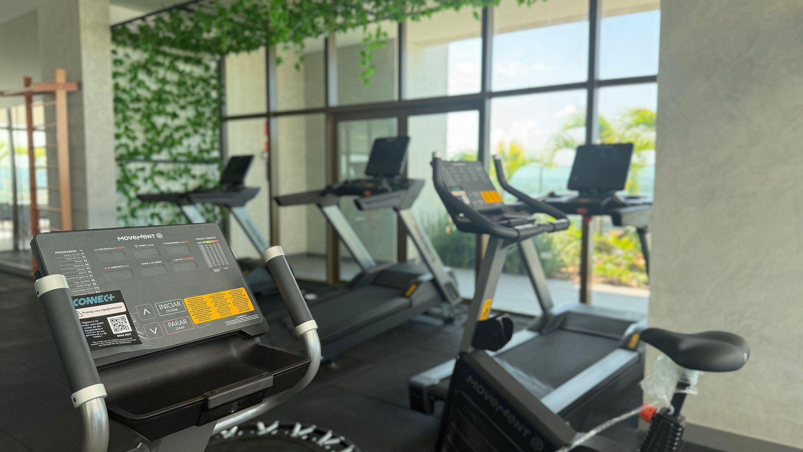 Un gimnasio con cintas de correr y una bicicleta estática, que incluye un panel de control con datos de entrenamiento.