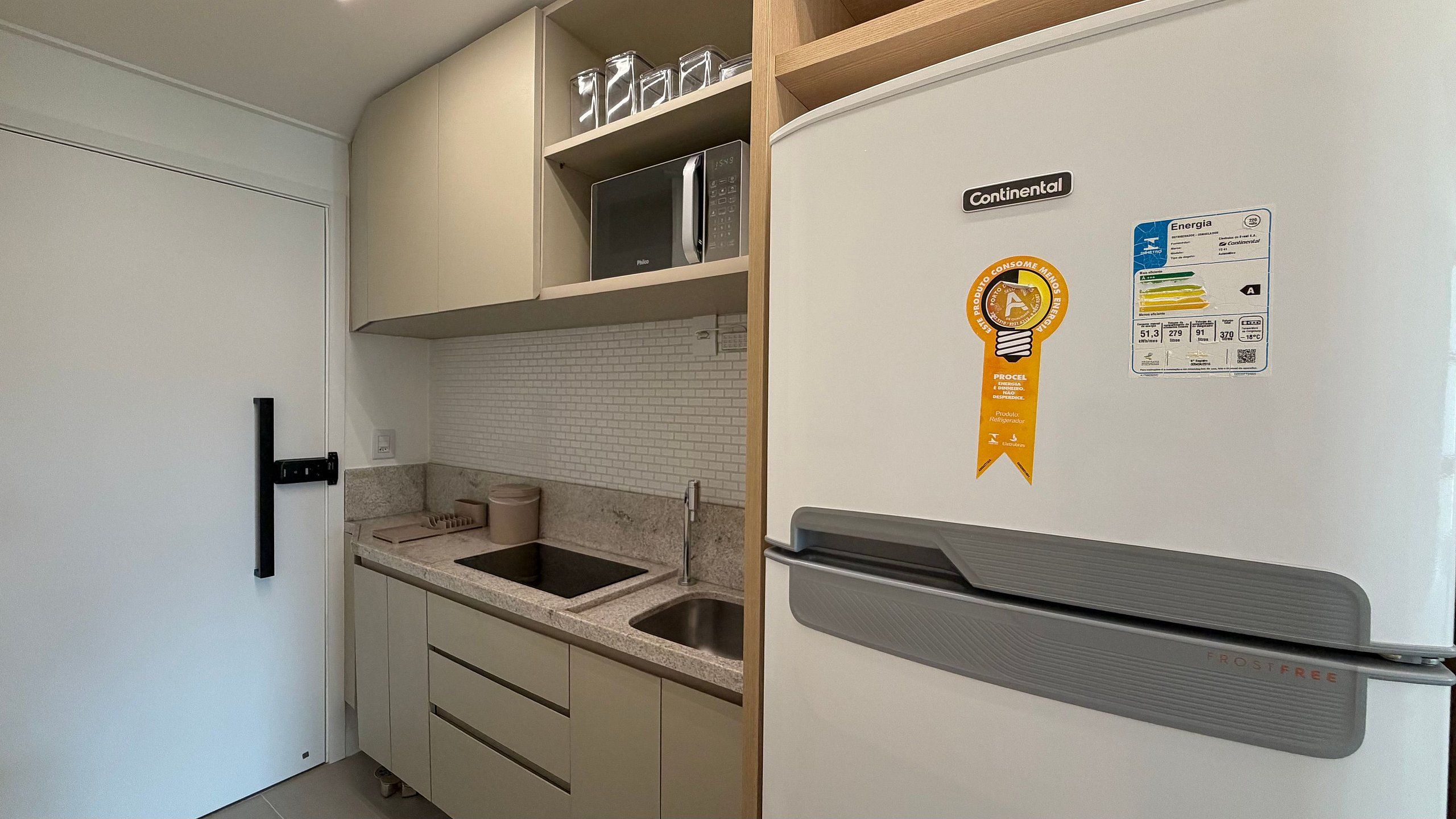 Eine kleine Küche mit Kühlschrank, Spüle und Arbeitsplatte.