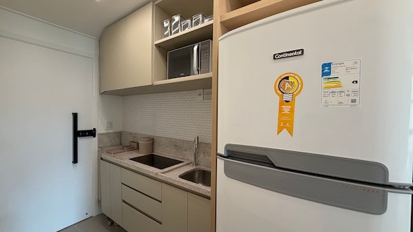 A compact kitchen with a refrigerator, a sink, and a countertop.