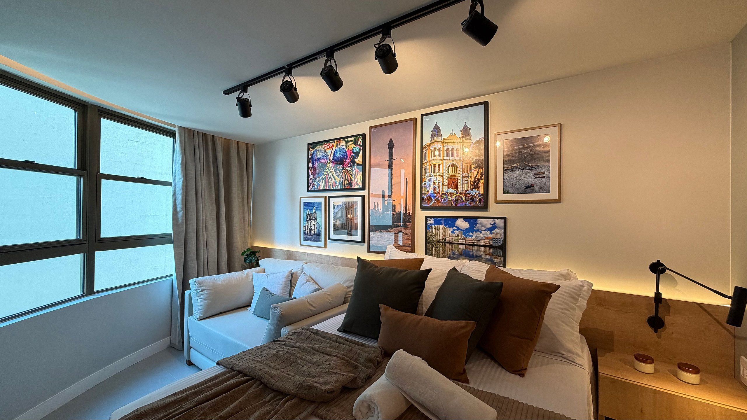 A modern bedroom with a bed, a sofa, and a large window.